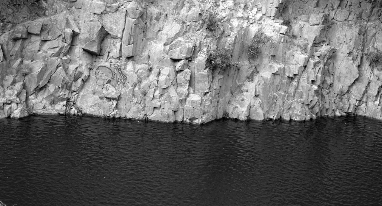 Where dark water and steep rock wall meet